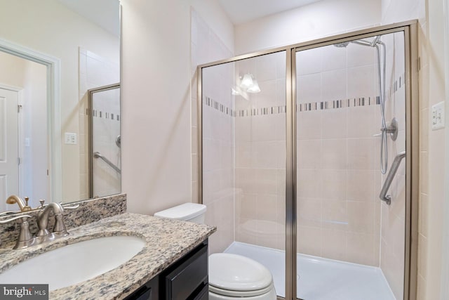 bathroom featuring toilet, a shower with shower door, and vanity