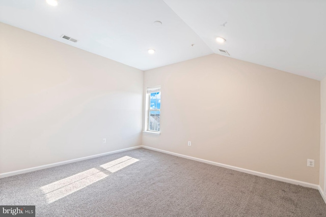 carpeted empty room featuring vaulted ceiling