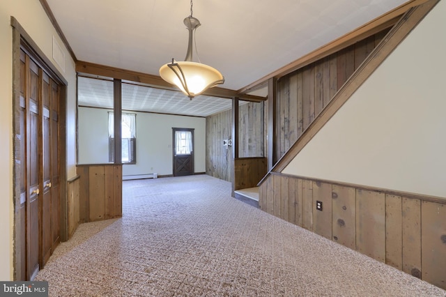 carpeted foyer entrance with wooden walls and a baseboard heating unit