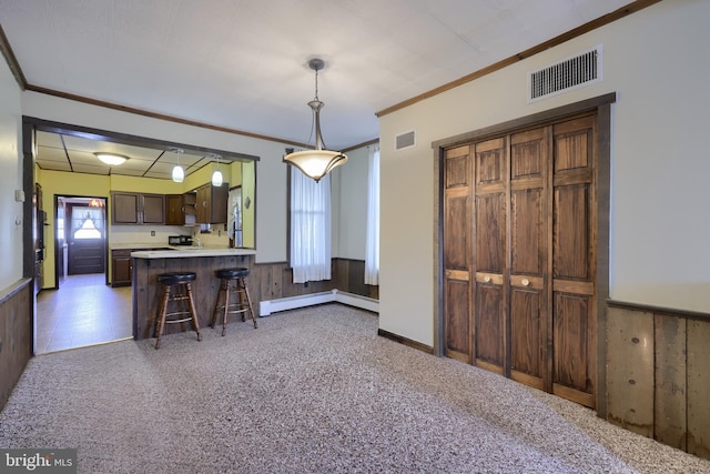 kitchen featuring wooden walls, light colored carpet, a kitchen bar, and baseboard heating