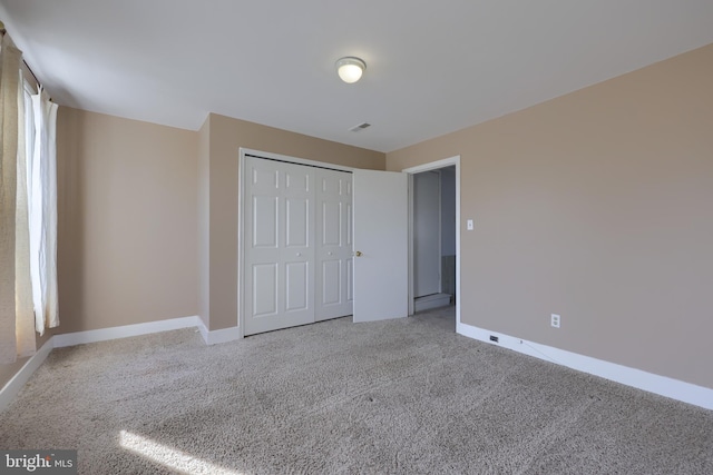 unfurnished bedroom featuring light carpet and a closet