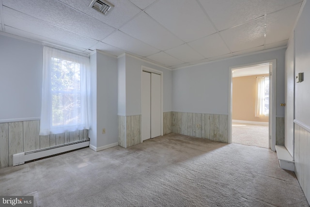 spare room featuring a baseboard heating unit, a paneled ceiling, light colored carpet, and wood walls