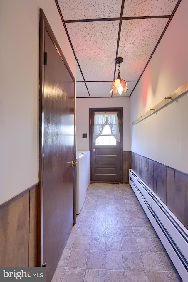 entryway with a baseboard heating unit, washer / dryer, a paneled ceiling, and wood walls