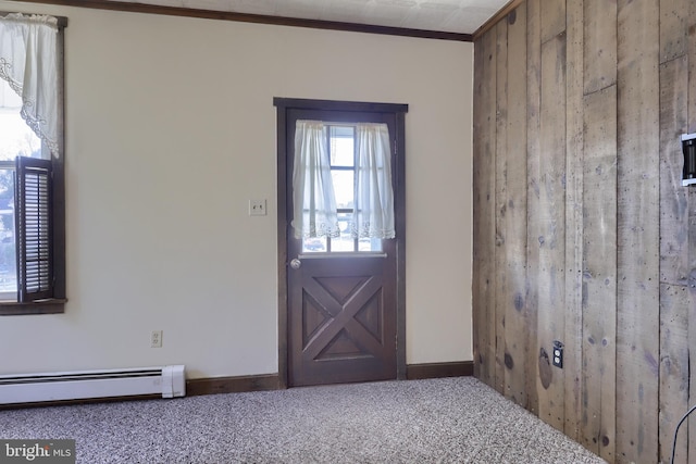 carpeted foyer with a baseboard heating unit, crown molding, and wooden walls