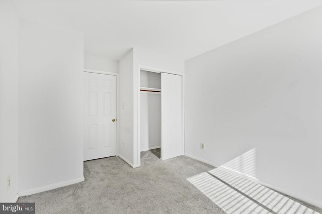 unfurnished bedroom with a closet and light colored carpet