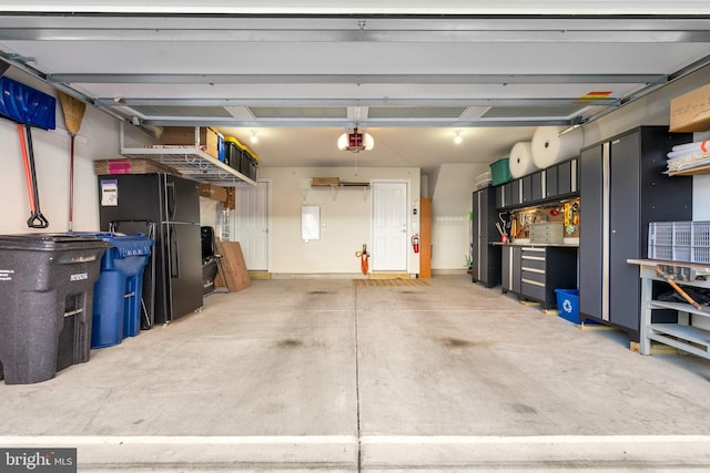 garage with a garage door opener and freestanding refrigerator