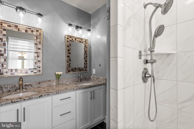 full bathroom with a sink, double vanity, and a tile shower