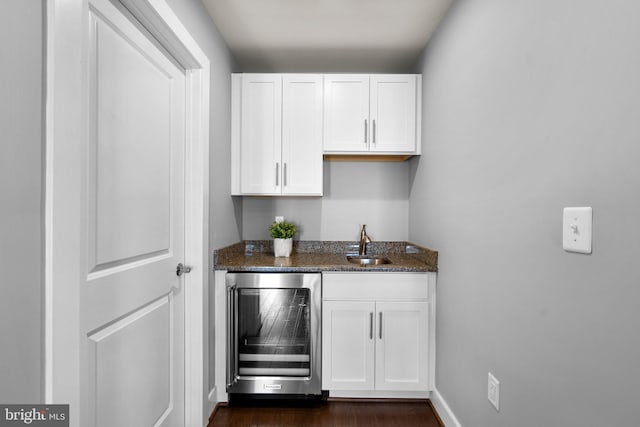 bar featuring wine cooler, dark wood finished floors, baseboards, and a sink