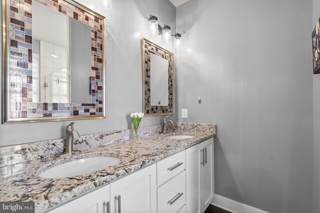 full bath featuring double vanity, baseboards, and a sink