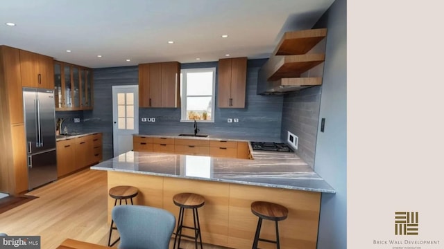 kitchen featuring sink, backsplash, a kitchen breakfast bar, stainless steel appliances, and kitchen peninsula