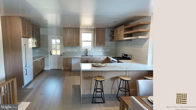 kitchen with sink, light wood-type flooring, kitchen peninsula, white appliances, and backsplash