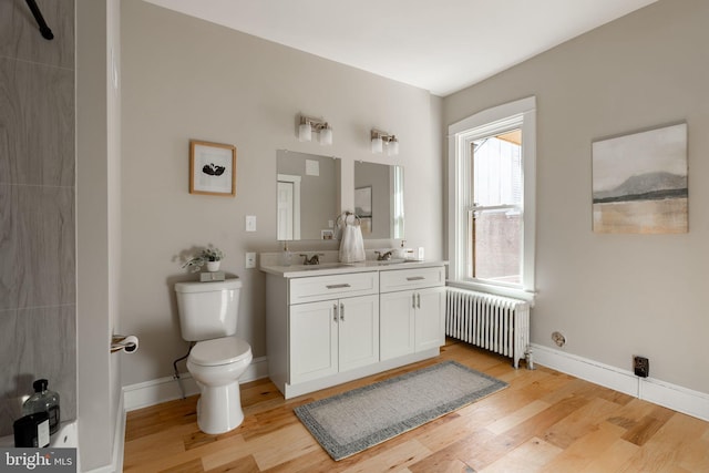 bathroom with wood-type flooring, radiator, vanity, and toilet