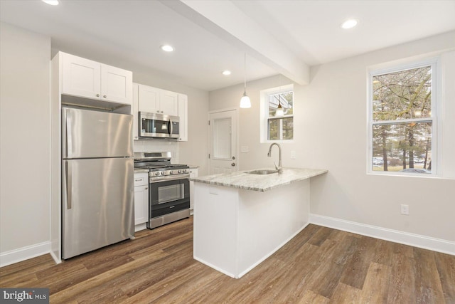 kitchen featuring white cabinetry, kitchen peninsula, stainless steel appliances, sink, and light stone counters