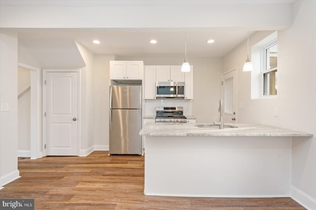 kitchen featuring white cabinetry, kitchen peninsula, stainless steel appliances, light stone countertops, and sink