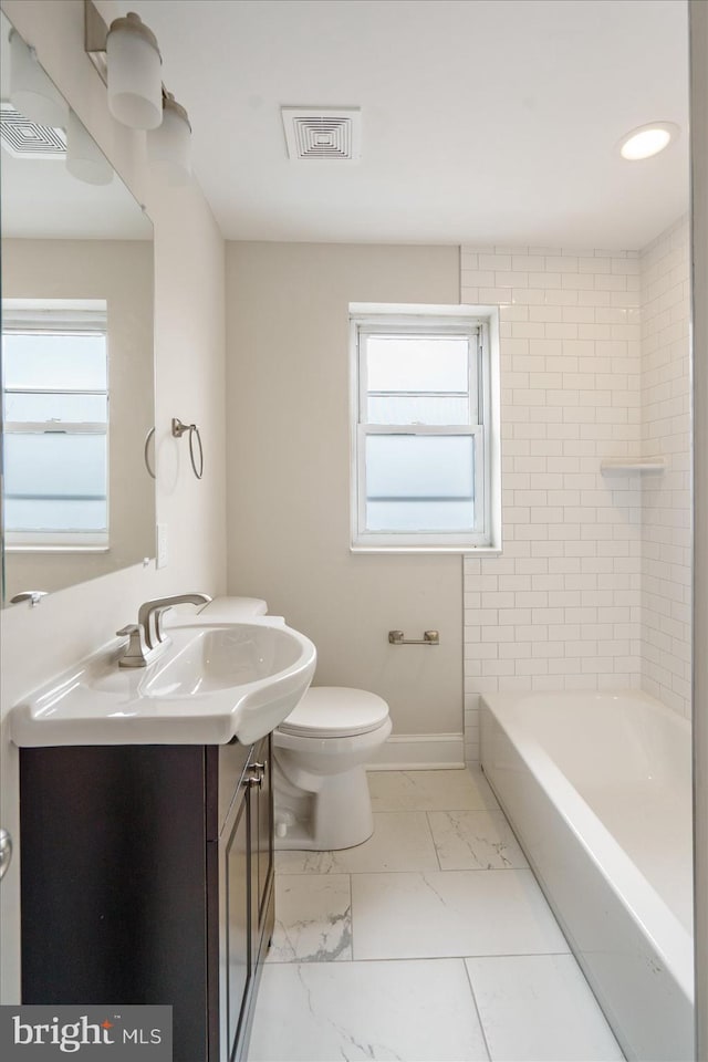 full bathroom featuring toilet, vanity, and tiled shower / bath