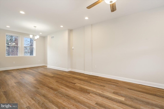 empty room with hardwood / wood-style floors and ceiling fan with notable chandelier