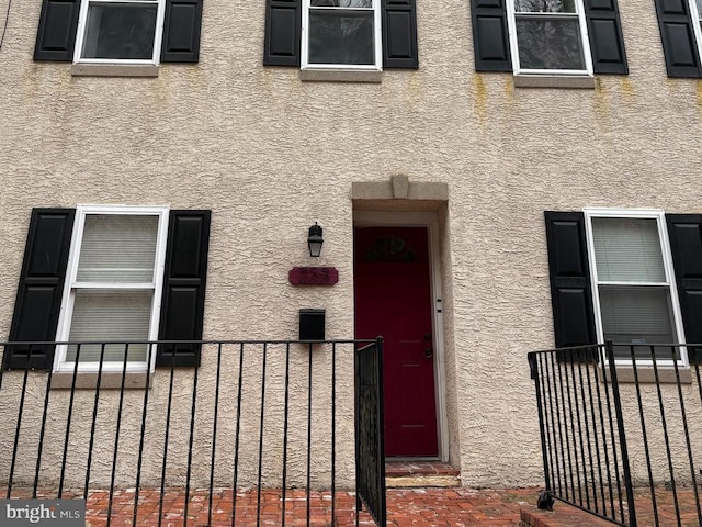 doorway to property with fence and stucco siding