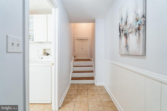 corridor featuring stairs, washer / clothes dryer, a wainscoted wall, and light tile patterned floors