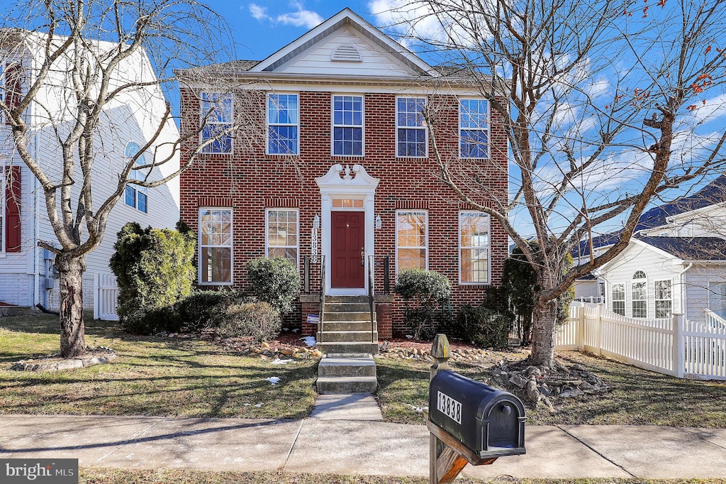 view of front facade featuring a front yard, fence, and brick siding