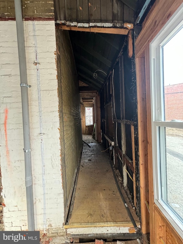 misc room featuring vaulted ceiling and brick wall