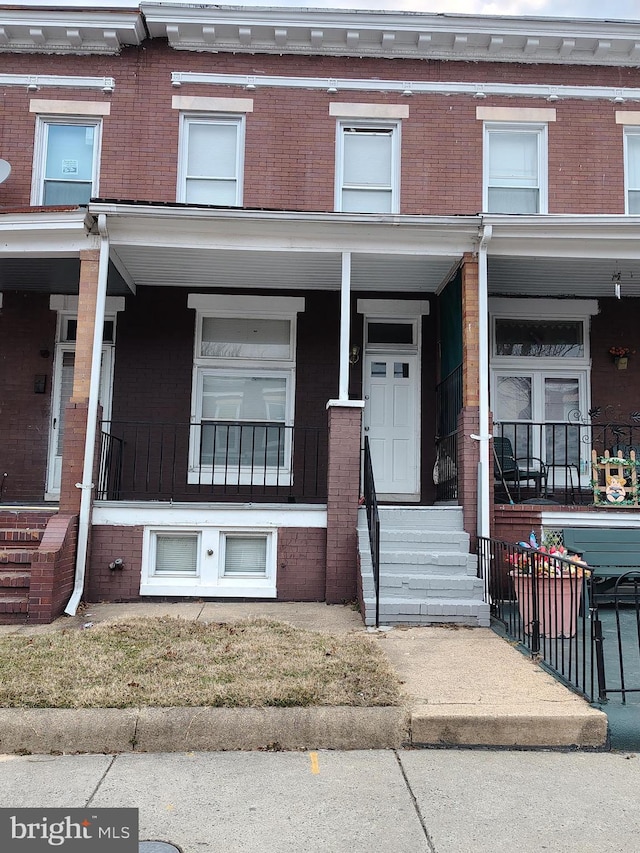 townhome / multi-family property featuring a porch and brick siding