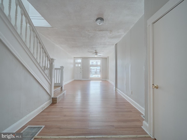 foyer entrance with stairway, wood finished floors, visible vents, and baseboards