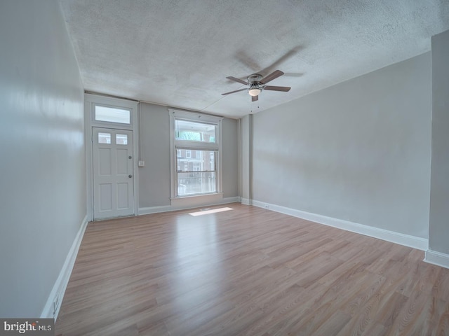 interior space with ceiling fan, a textured ceiling, baseboards, and wood finished floors