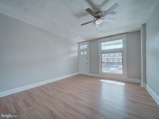 empty room with a ceiling fan, a textured ceiling, baseboards, and wood finished floors