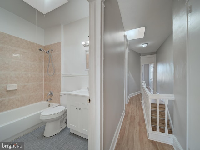 full bath featuring toilet, a skylight, vanity, baseboards, and shower / bathing tub combination