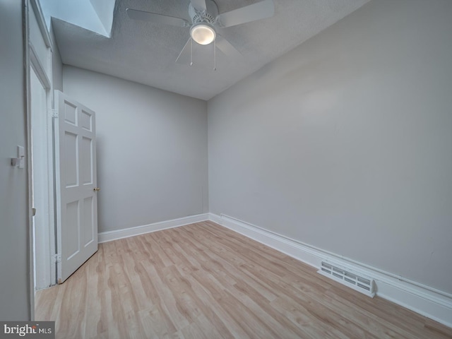 spare room featuring baseboards, visible vents, ceiling fan, wood finished floors, and a textured ceiling