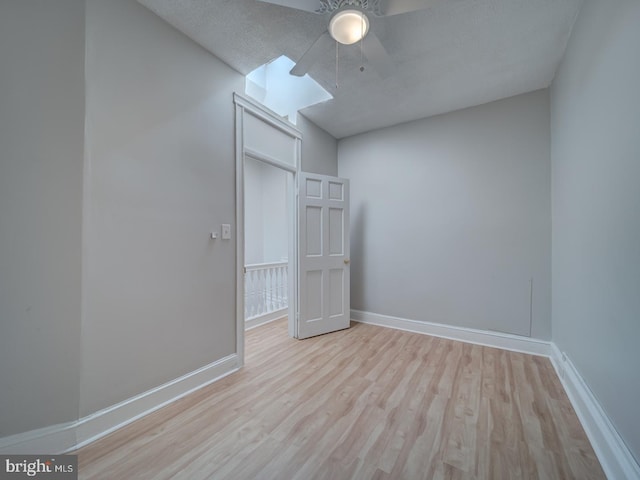 unfurnished bedroom featuring ceiling fan, a textured ceiling, baseboards, and wood finished floors