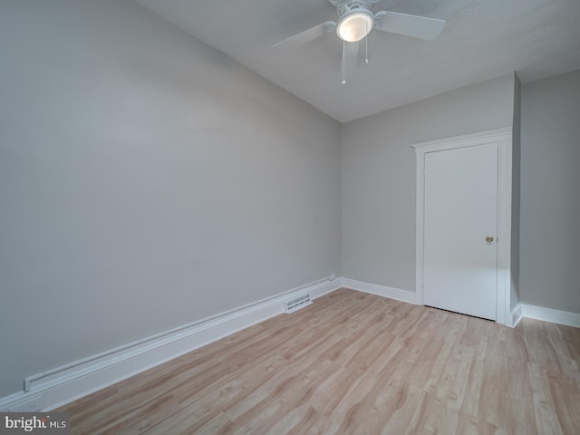 spare room with light wood finished floors, baseboards, visible vents, and a ceiling fan