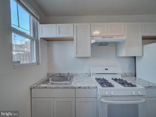 kitchen featuring under cabinet range hood, white cabinetry, a sink, and white gas stove