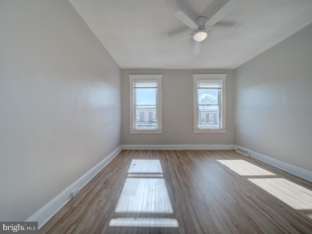 unfurnished room featuring baseboards, visible vents, ceiling fan, and wood finished floors