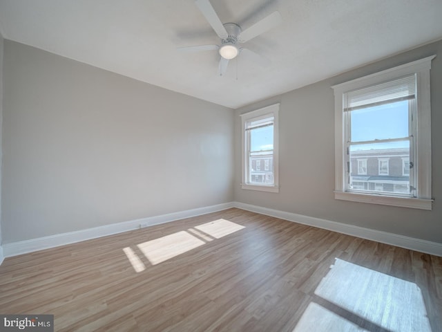 spare room featuring ceiling fan, light wood finished floors, and baseboards