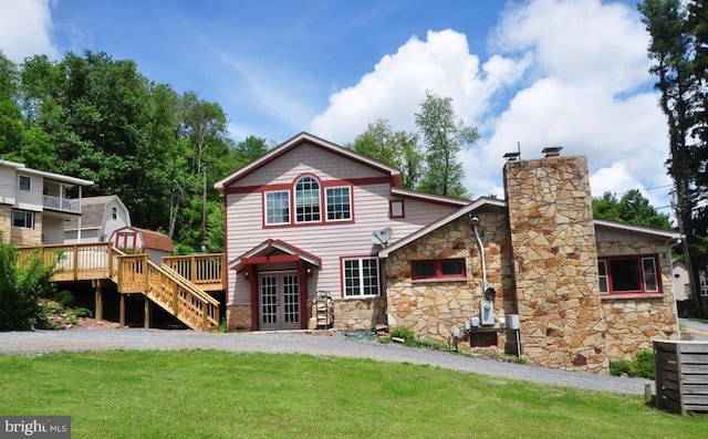 view of front of house with a wooden deck, french doors, stone siding, stairway, and a yard