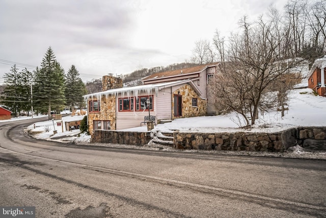 view of front facade with stone siding and a chimney