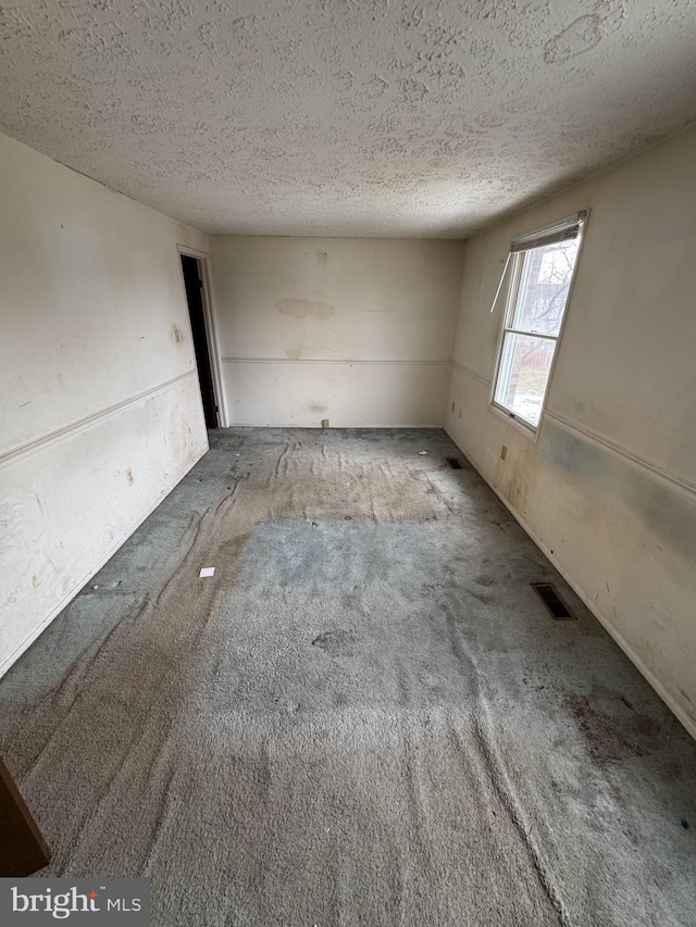 carpeted spare room with a textured ceiling