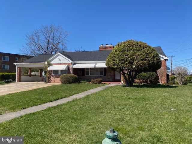 view of front of house featuring a front lawn, concrete driveway, and a carport