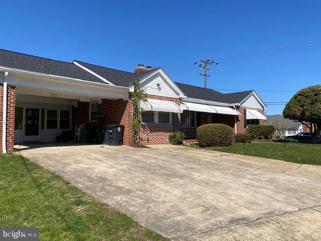 view of front of home with a front yard, brick siding, and a chimney