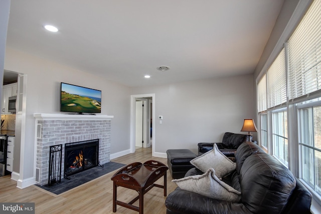 living room featuring a brick fireplace and light hardwood / wood-style flooring