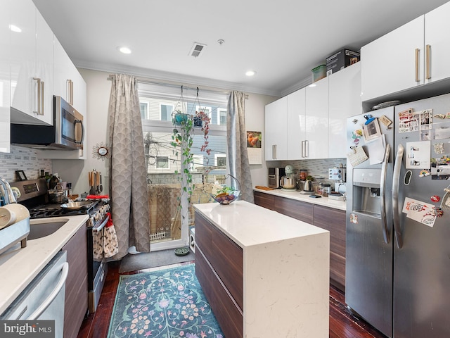 kitchen featuring ornamental molding, appliances with stainless steel finishes, and white cabinets