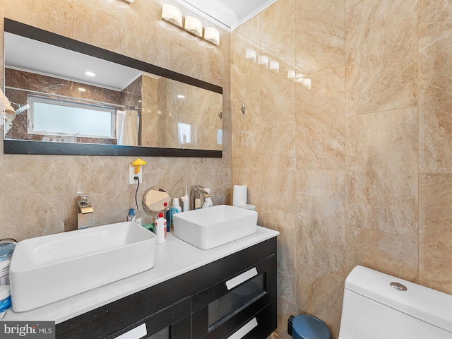 bathroom with vanity, toilet, a shower with shower curtain, and tile walls