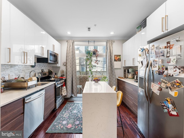 kitchen with white cabinetry, decorative backsplash, a breakfast bar area, and appliances with stainless steel finishes