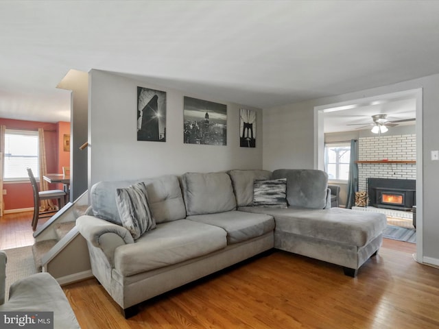 living area featuring a brick fireplace, plenty of natural light, and wood finished floors