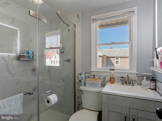 bathroom featuring vanity, a marble finish shower, toilet, and tile walls