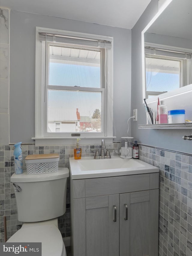 bathroom featuring wainscoting, plenty of natural light, tile walls, and toilet