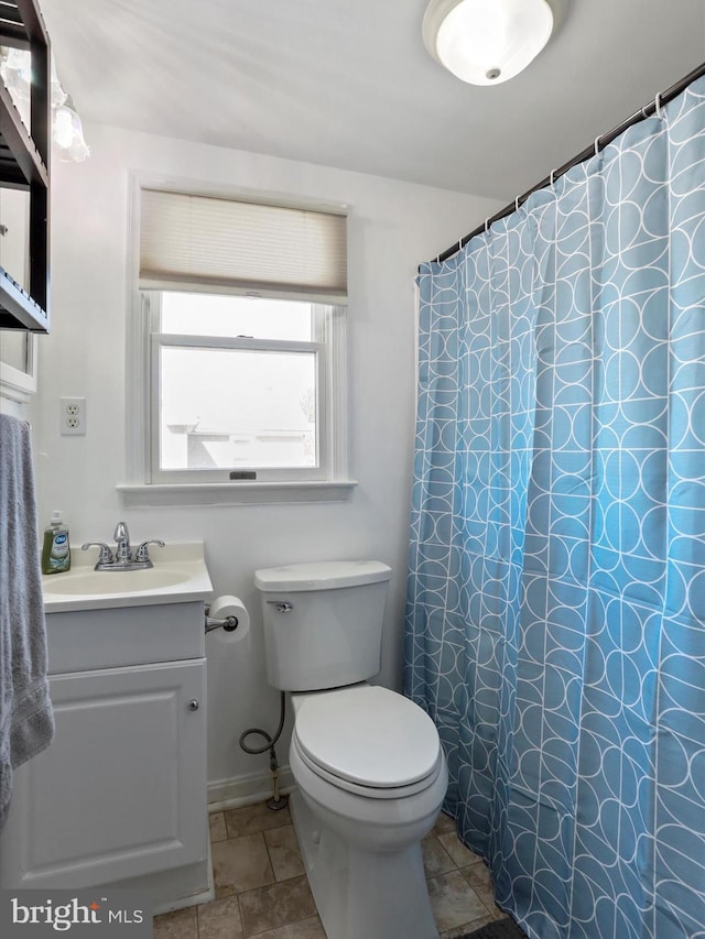 bathroom featuring toilet, vanity, a shower with curtain, baseboards, and tile patterned floors