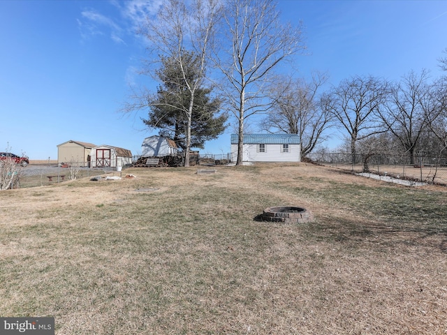 view of yard with an outdoor fire pit, fence, and an outdoor structure