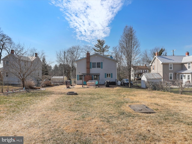 rear view of property featuring a fire pit, fence, a pergola, and a lawn